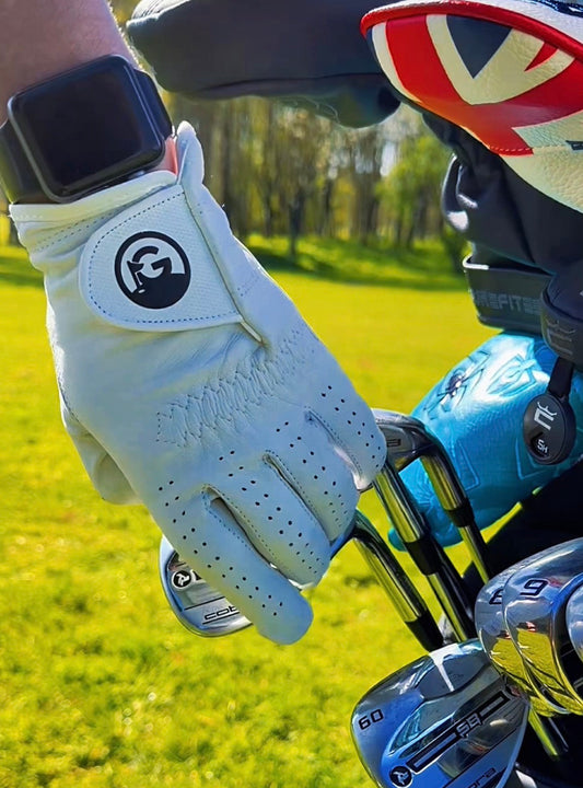 Golf club with a gloved hand and golf bag in the background on a golf course.